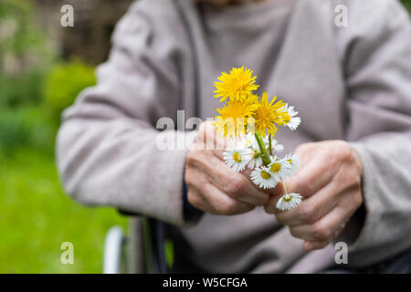 In der Nähe Bild von älteren Menschen die Hände schütteln Holding Blumenstrauß Stockfoto
