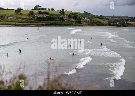 Juli 27th, 2019, Clonakilty, Irland - einen Panoramablick auf die inchydoney Strand an einem bewölkten Tag mit Menschen surfen, schwimmen und Schwimmen Stockfoto