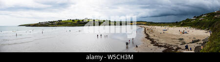 Juli 27th, 2019, Clonakilty, Irland - einen Panoramablick auf die inchydoney Strand an einem bewölkten Tag mit Menschen surfen, schwimmen und genießen den Krieg Stockfoto