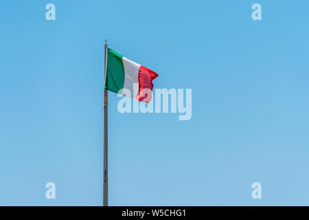 Eine italienische Fahne in den Wind gegen einen strahlend blauen Himmel Stockfoto