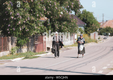 Bontida, Rumänien - Juli 21, 2019: Ein älteres Ehepaar auf einer leeren Straße in ein Dorf im ländlichen Rumänien an einem heißen hellen Sommertag Stockfoto