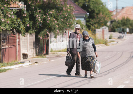 Bontida, Rumänien - Juli 21, 2019: Ein älteres Ehepaar auf einer leeren Straße in ein Dorf im ländlichen Rumänien an einem heißen hellen Sommertag Stockfoto