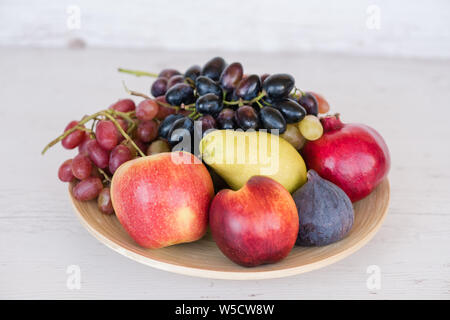 Frische, süße Früchte in eine hölzerne Platte auf einem weißen Hintergrund. Stockfoto