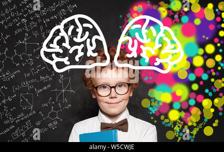 Happy little boy tragen weiße Hemd und Brille in der Nähe der Tafel stand mit bunten Gehirn Skizze Hand gezeichnet. Konzept des kreativen Denkens und Educ Stockfoto