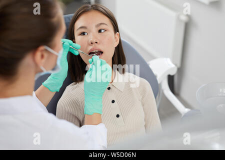 Hohen winkel Portrait von asiatischen Mädchen im Behandlungsstuhl liegen mit weiblichen Zahnarzt Zähne untersuchen, kopieren Raum Stockfoto