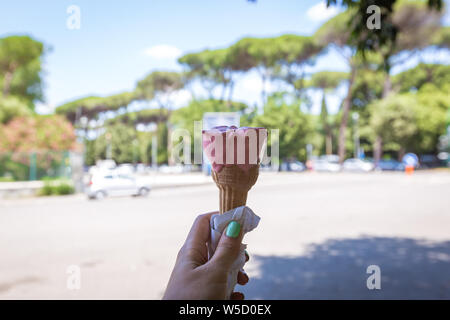 Weibliche Hand, die italienische Eis mit italienischen Straße als Hintergrund Stockfoto