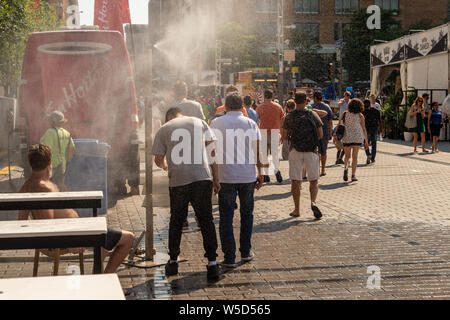 Montreal, CA - 27. Juli 2019: Menschen gehen unter Beschlag System abkühlt (Nebel Kühlsystem) während der Hitzewelle in Quartier des Festivals. Stockfoto