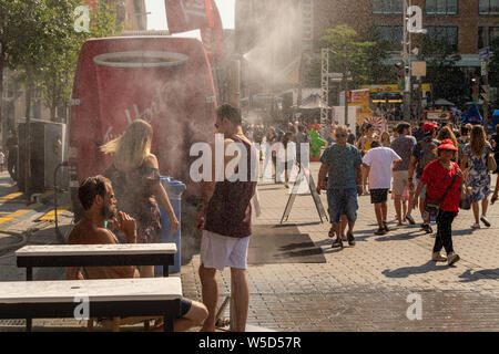 Montreal, CA - 27. Juli 2019: Menschen gehen unter Beschlag System abkühlt (Nebel Kühlsystem) während der Hitzewelle in Quartier des Festivals. Stockfoto