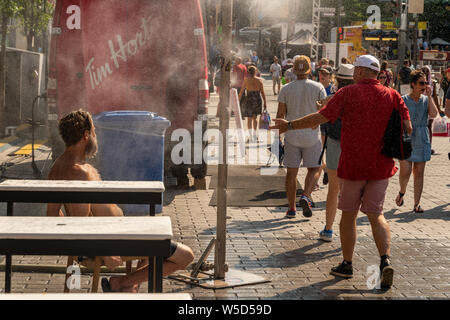 Montreal, CA - 27. Juli 2019: Menschen gehen unter Beschlag System abkühlt (Nebel Kühlsystem) während der Hitzewelle in Quartier des Festivals. Stockfoto