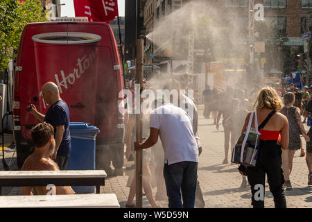 Montreal, CA - 27. Juli 2019: Menschen gehen unter Beschlag System abkühlt (Nebel Kühlsystem) während der Hitzewelle in Quartier des Festivals. Stockfoto