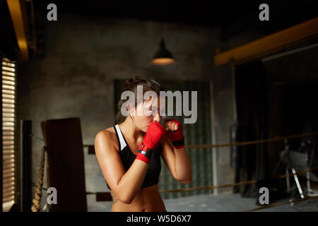 Dramatische Seitenansicht Portrait von harten weiblichen Boxer üben im Boxring, Kopie Raum Stockfoto