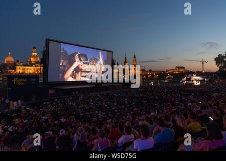 24 Juli 2019, Sachsen, Dresden: Zahlreiche Gäste der "Filmnächte am Elbufer" sitzen vor der Kulisse der Dresdner Altstadt mit der Kuppel des Kunstakedemie (L-R), der Frauenkirche, der hausmannsturm, der Hofkirche, der Semperoper und im Kino. Foto: Robert Michael/dpa-Zentralbild/dpa Stockfoto