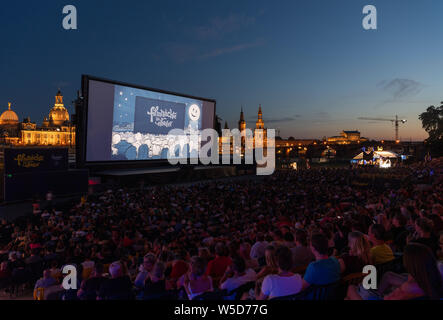 24 Juli 2019, Sachsen, Dresden: Zahlreiche Gäste der "Filmnächte am Elbufer" sitzen vor der Kulisse der Dresdner Altstadt mit der Kuppel des Kunstakedemie (L-R), der Frauenkirche, der hausmannsturm, der Hofkirche, der Semperoper und im Kino. Foto: Robert Michael/dpa-Zentralbild/dpa Stockfoto