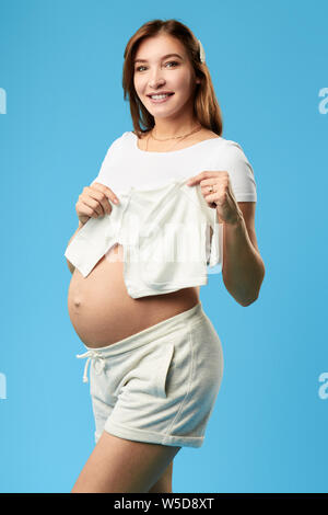 Ziemlich schöne schöne fröhliches Mädchen Vorbereitung für die Geburt, bis Portrait schließen. Isoliert blau bacground. Studio gedreht. Stockfoto