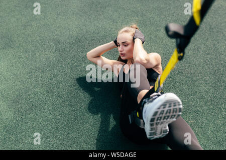 Hohe Betrachtungswinkel und der Sportlerin, Abdominal- Übungen mit Suspension Riemen Stockfoto