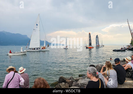 Vevey, Schweiz - 26. Juli 2019: Leute beobachten festliche Segelboote während der Fete des Vignerons 2019. Traditionelles Festival ist eine Hommage an die Traditionen des Weinsektors im Lavaux Wein Region. Organisiert einmal in 20-25 Jahren, einmal in einer Generation, seit dem 18. Jahrhundert. Es war, als die ersten lebendigen Tradition in der Schweiz erhielt UNESCO-Anerkennung geehrt. Festival findet vom 18.Juli bis 11. August 2019. Stockfoto