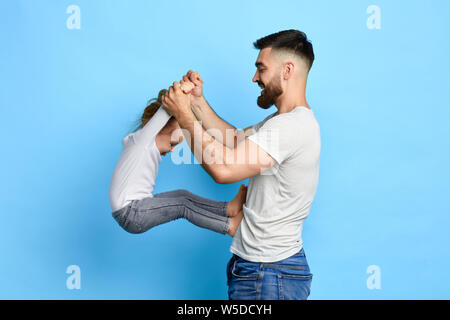 Happy awesome Vati Übungen mit Tochter. close up Side View Photo. Isolierte blauen Hintergrund. Studio erschossen. sport, gesunde Lebensweise. Hobby, Freizeit. Freizeit Stockfoto