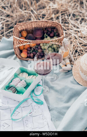 Zwei Gläser Rotwein, Obst und Süßigkeiten auf dem Sunset Picknick. Ansicht von oben. Stockfoto