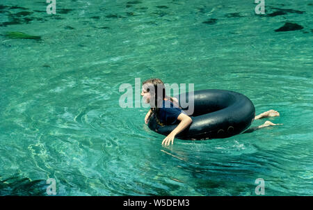 Ein junges Mädchen hat Spaß floating in einem LKW-Reifen inneren Rohr nach unten der Frühling - FBI Ichetucknee Fluss im nördlichen Florida, USA. Tubing ist der Favorit Erholung von Tausenden Sommer Besucher Ichetucknee Springs State Park, wo acht großen kristallinen Federn zusammen melden Sie erstellen die sechs Meilen (9,6 Kilometer) Fluss. Menschen aller Altersgruppen, gemütliche Fahrten mit ringförmigen aufblasbaren Gummi oder Kunststoff Rohre in die unberührten Gewässer, dass eine National Natural Landmark 1972 deklariert wurden. Entlang der Weise an ruhigen Tagen, Knollen erkennt vielleicht vielfältige Tierwelt des Parks. Stockfoto