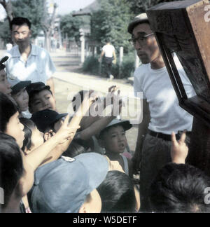 [1960s Japan - Japanische Kamishibai Geschichtenerzähler] - japanische Kinder reagieren auf ein kamishibai Leistung, 1960 (Showa 35). Kamishibai Geschichtenerzähler reiste auf einem Fahrrad mit einem kleinen Bühne ausgestattet und verdienten ihr Geld mit dem Verkauf von Süßigkeiten. Dies ist ein Scan eines drucken und die Qualität ist niedrig. Stockfoto