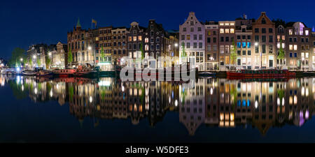 Panorama der Reflexion der Gebäude entlang des Kanals in der Nacht in Amsterdam, Niederlande Stockfoto