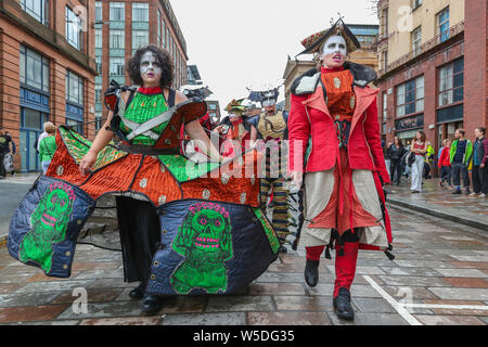 Glasgow, Schottland, Großbritannien. 28. Juli 2019. Nach starkem Regen verursacht einige Unterhaltung zu stornieren, OCEANALLOVER, einer internationalen Street Unterhaltung Theater, nutzten eine kurze Atempause im Regen und unterhalten die Massen in der Brunswick Street mit ihrem Spiel "verklärt". Credit: Findlay/Alamy leben Nachrichten Stockfoto