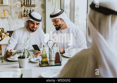 Drei Männer mit einem Tee in Dubai, die traditionelle emiratische Kleidung Stockfoto