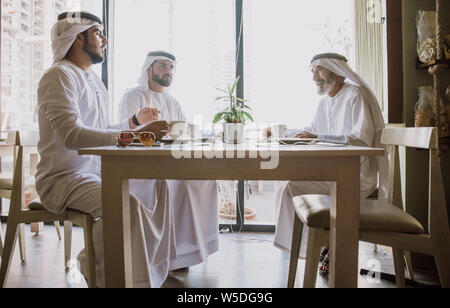 Drei Männer mit einem Tee in Dubai, die traditionelle emiratische Kleidung Stockfoto