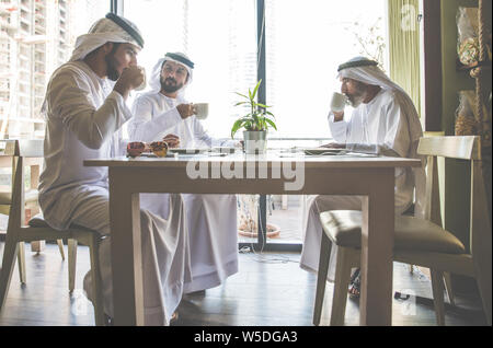 Drei Männer mit einem Tee in Dubai, die traditionelle emiratische Kleidung Stockfoto