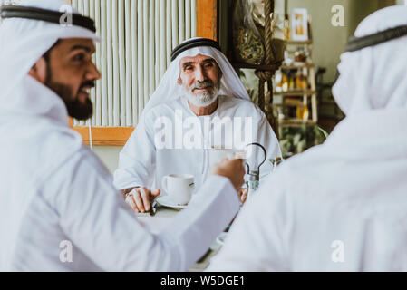 Drei Männer mit einem Tee in Dubai, die traditionelle emiratische Kleidung Stockfoto