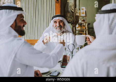 Drei Männer mit einem Tee in Dubai, die traditionelle emiratische Kleidung Stockfoto