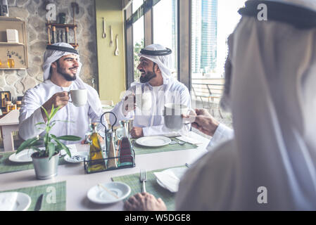 Drei Männer mit einem Tee in Dubai, die traditionelle emiratische Kleidung Stockfoto