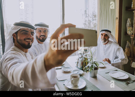 Drei Männer mit einem Tee in Dubai, die traditionelle emiratische Kleidung Stockfoto