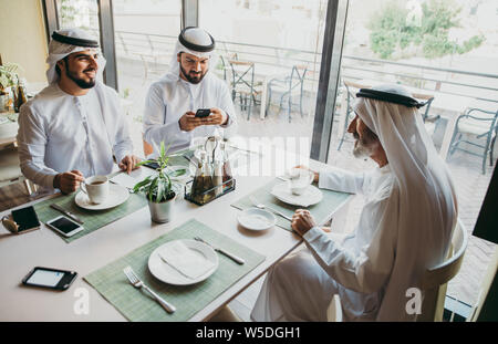 Drei Männer mit einem Tee in Dubai, die traditionelle emiratische Kleidung Stockfoto