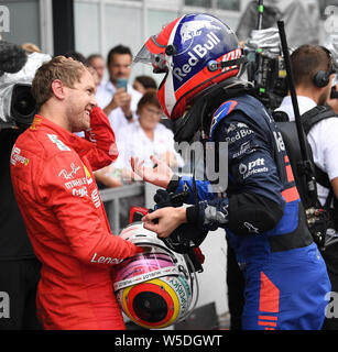 Hockenheim, Deutschland. 28. Juli 2019. Motorsport: Formel 1-Weltmeisterschaft, den grossen Preis von Deutschland. Zweitplatzierte Sebastian Vettel aus Deutschland vom Team Scuderia Ferrari lächelt als er spricht mit dem Drittplatzierten Daniil Kvyat aus Russland von Team Red Bull Toro Rosso Honda nach dem Rennen. Credit: Sebastian Gollnow/dpa/Alamy leben Nachrichten Stockfoto