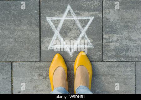 Weibliche Füße mit abstrakten Bild von sechs Stern, auf grau Bürgersteig geschrieben. Stockfoto