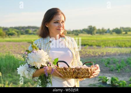 Outdoor Portrait von Bauer Frau mit Korb mit frischem huhn eier, Bauernhof, Gemüsegarten, Hintergrund, goldene Stunde Stockfoto