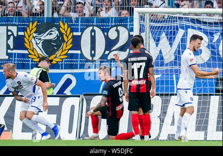 28 Juli 2019, Hessen, Wiesbaden: Fussball: 2. Bundesliga, SV Wehen Wiesbaden - Karlsruher SC, 1. Spieltag, in der BRITA-Arena. Der Karlsruher Philipp Hofmann (l) jubelt nach seinem Tor zum 0:2. Manuel Schäffler (2. von links) und Daniel-Kofi Kyereh (2. von rechts) aus Wiesbaden sind weiter. Foto: Uwe Anspach/dpa - WICHTIGER HINWEIS: In Übereinstimmung mit den Anforderungen der DFL Deutsche Fußball Liga oder der DFB Deutscher Fußball-Bund ist es untersagt, zu verwenden oder verwendet Fotos im Stadion und/oder das Spiel in Form von Bildern und/oder Videos - wie Foto Sequenzen getroffen haben. Stockfoto