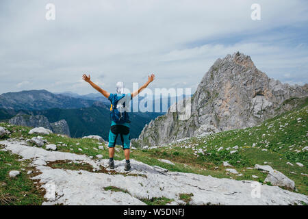 Wanderer Mann mit den Händen oben stehen das Erreichen der Spitze. Konzeption. Erfolgreicher mann Wanderer mit offenen Armen auf. Mann in Sportkleidung in der mounta Stockfoto
