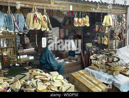 [1920s Japan - Japanische schuhe Shop] - ein Geschäft mit Geta, Japanischer Holz- Schuh tragen. Die Wurzeln der geta Zurück zur yayoi Ära, aber sie wurde besonders populär in der Edo Periode (1600 - 1868). Geta Handwerker angeboten eine Vielzahl von Geta, abhängig von der Mode der Zeit. 20. Jahrhundert vintage Glas schieben. Stockfoto