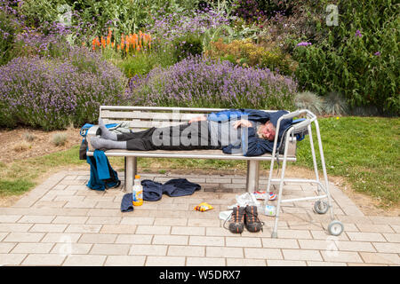 Obdachlosen Person schlafen im Freien auf einer Parkbank in der Parklandschaft in Stratford-upon-Avon, Warwickshire, England Stockfoto