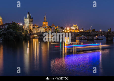 Altstadt Turm und die historische steinerne Brücke mit Beleuchtung und Reflexionen aus dem Schiff auf dem Wasser. Prag mit Charles Bridge bei Nacht. Panoramaaussicht Stockfoto