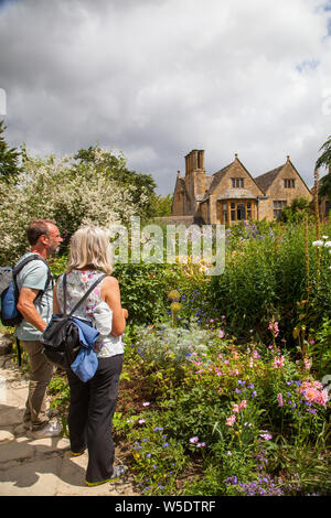 Die Menschen genießen den Tag in der National Trust Eigentum von Hidcote Manor Gardens mit ihren krautigen Blumenrabatten in den englischen Cotswolds Stockfoto