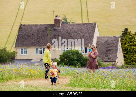 Familie und Kinder in wildflower Wiese vor ein Landhaus Stockfoto