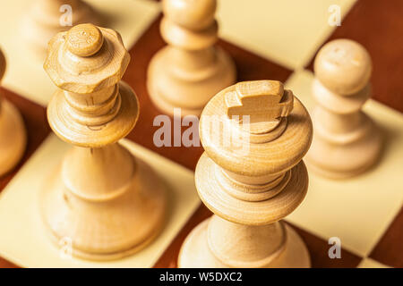 Makroaufnahme der Schachfiguren mit Oberseite der weisse König und Königin schräg von oben im Fokus und die Bauern aus der Fokus in den Hintergrund betrachtet. Stockfoto