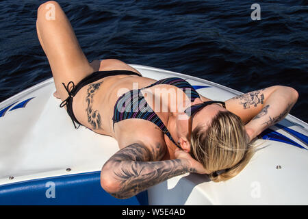 Blond kaukasische Frau Sonnen Deck auf einem Boot auf einem See im Sommer Stockfoto