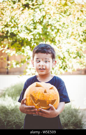 Halloween 2019. Little boy Holding geschnitzten Halloween Kürbis - Jack O'Lanterns im Außenbereich. Familie Vorbereitungen für Halloween Urlaub. Stockfoto