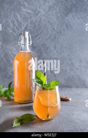 Hausgemachte Kombucha gesund lecker Getränk in der Flasche und Glas mit Zitrone Minze garnieren. Bio probiotische Drink, kopieren. Stockfoto