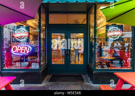 ASHEVILLE, NC, USA-16 Feb.2019: Burgerworx, 1 Seite Avenue, im frühen Abend. Bild aufgenommen von innen durch das vordere Fenster, mit Reflexionen von Stockfoto