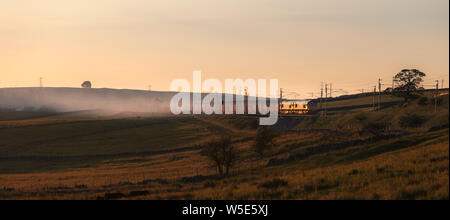 2 DB Cargo Baureihe 66 Diesellokomotiven an Shap Wells auf der West Coast Mainline in Cumbria mit einem Güterzug Kalk Durchführung bei Sonnenuntergang Stockfoto